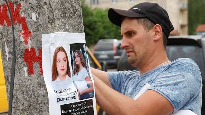 Seorang warga Ukraina memasang informasi orang hilang/ Reuters