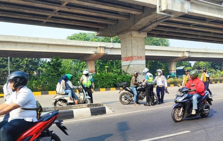 Dua orang personel Satlantas Polresta Jakarta Timur menghentikan pengendara sepeda motor yang melawan arah saat Operasi Lintas Jaya di putaran Lampiri, Kalimalang. (SinPo.id/Antraa)