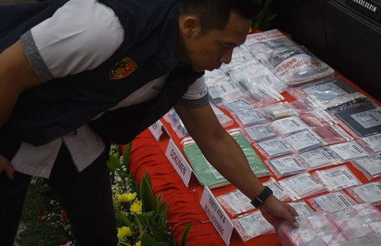 Petugas menata sejumlah barang bukti dalam konferensi pers kasus dugaan judi daring terkait kompetisi sepak bola Indonesia di Mabes Polri. (SinPo.id/Antara)