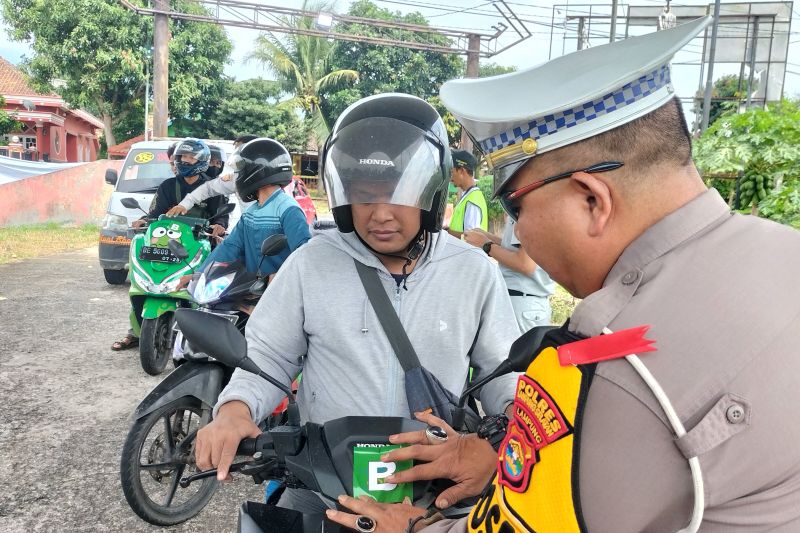 Suasana saat petugas melakukan pemasangan stiker di kendaraan pemudik yang akan melakukan penyeberangan menuju pulau Jawa. (SinPo.id/Antara)