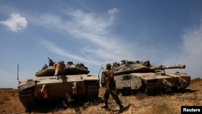 Tentara Israel berjalan di samping tank yang berada di dekat perbatasan Israel-Jalur Gaza (SinPo.id/Reuters)