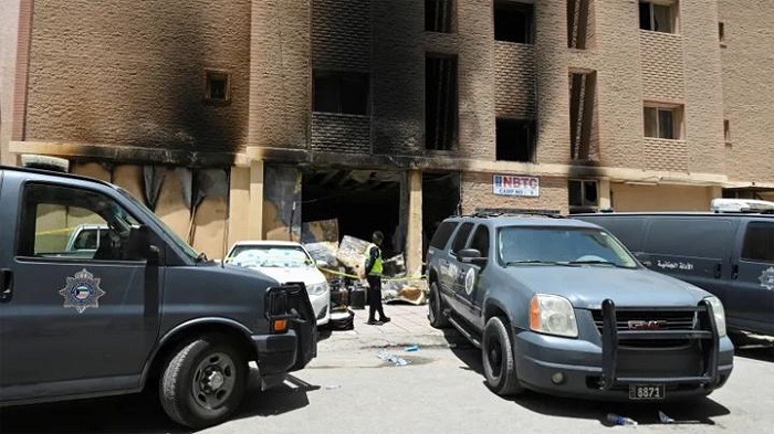 Seorang polisi terlihat di depan gedung yang terbakar di Mangaf, Kuwait. (SinPo.id/Reuters)