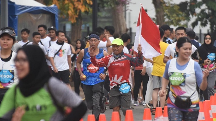 Peserta membawa bendera Merah Putih saat Electric Jakarta Marathon 2018 (SinPo.id/ Antara)