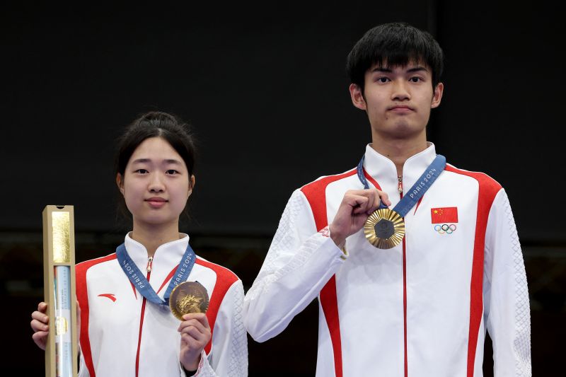 Huang Yuting dan Sheng Lihao berpose di podium kemenangan setelah mempersembahkan medali emas pertama untuk China dari Olimpiade Paris 2024. (SinPo.id/AFP)