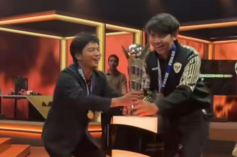 Ichsan Rahmat Taufiq sebagai manajer dan Budi Muhamad Manar Hidayat mengangkat trofi saat menjuarai ajang FIFAe World Cup 2024 Football Manager. (SinPo.id/Instagram @fifae)