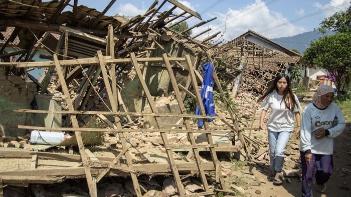 Warga melintas di dekat rumah yang rusak pasca gempa di Kabupaten Bandung. (SinPo.id/Antara)