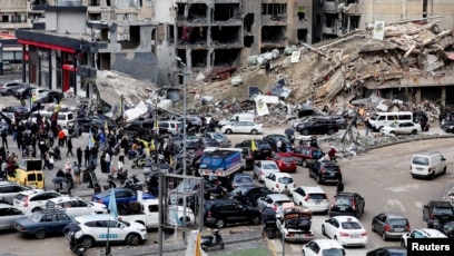 kendaraan melaju di dekat bangunan yang rusak, di pinggiran selatan Beirut (SinPo.id/Reuters)