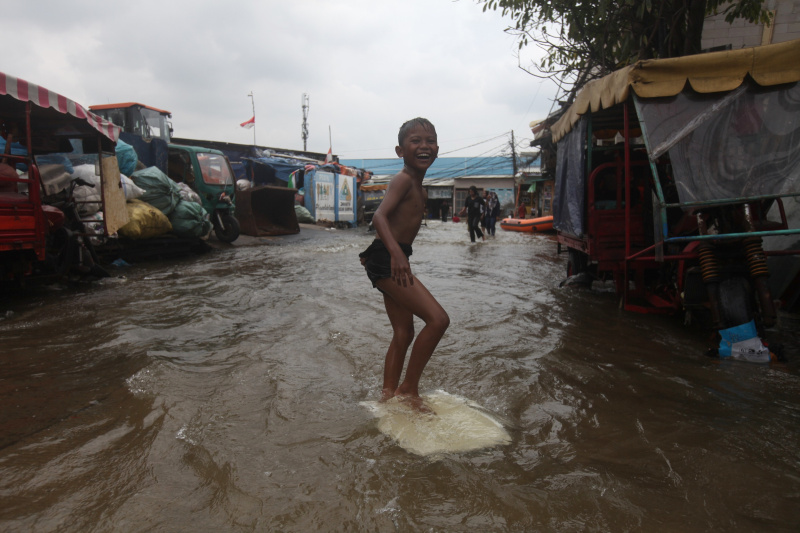 Ilustrasi. Sejumlah anak-anak sedang bermain banjir rob setinggi 30 Cm di Muara Angke (Ashar/SinPo.id)