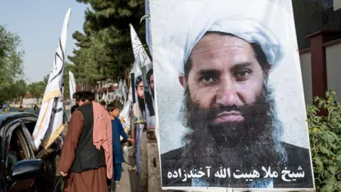 Poster foto pemimpin tertinggi Taliban di Afghanistan, Haibatullah Akhundzada. (SinPo.id/Getty Images)