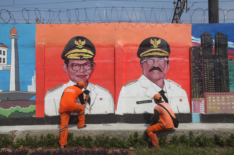 Pasukan Orange sedang mengerjakan mural wajah Gubernur DKI Jakarta dan Sambut HUT ke-500 tahun Kota Jakarta di Bukit Duri