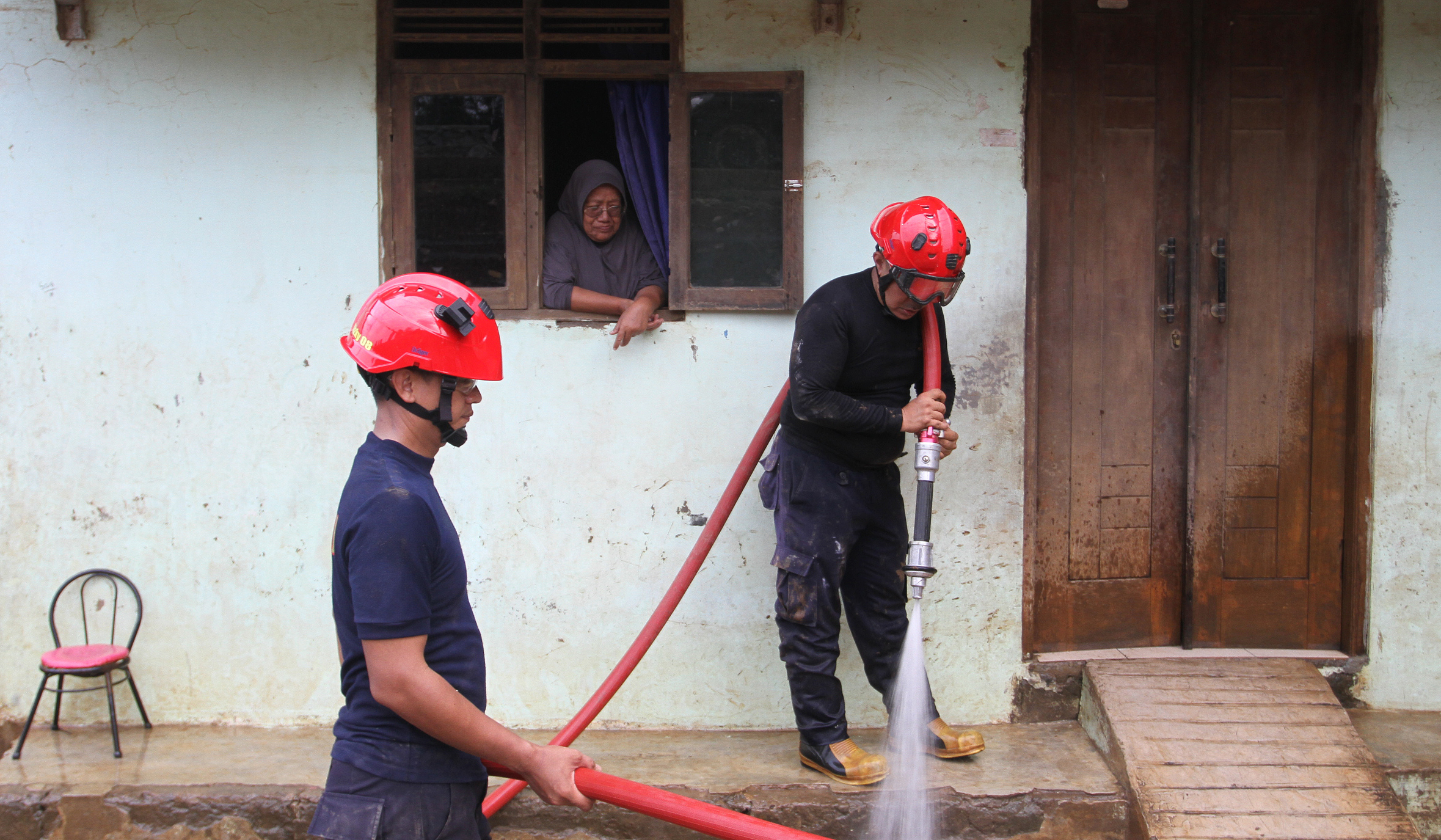 Petugas pemadam kebakaran (Damkar) membantu membersihkan lumpur sisa banjir di Rawajati, Jakarta, Senin (7 Juli 2025).