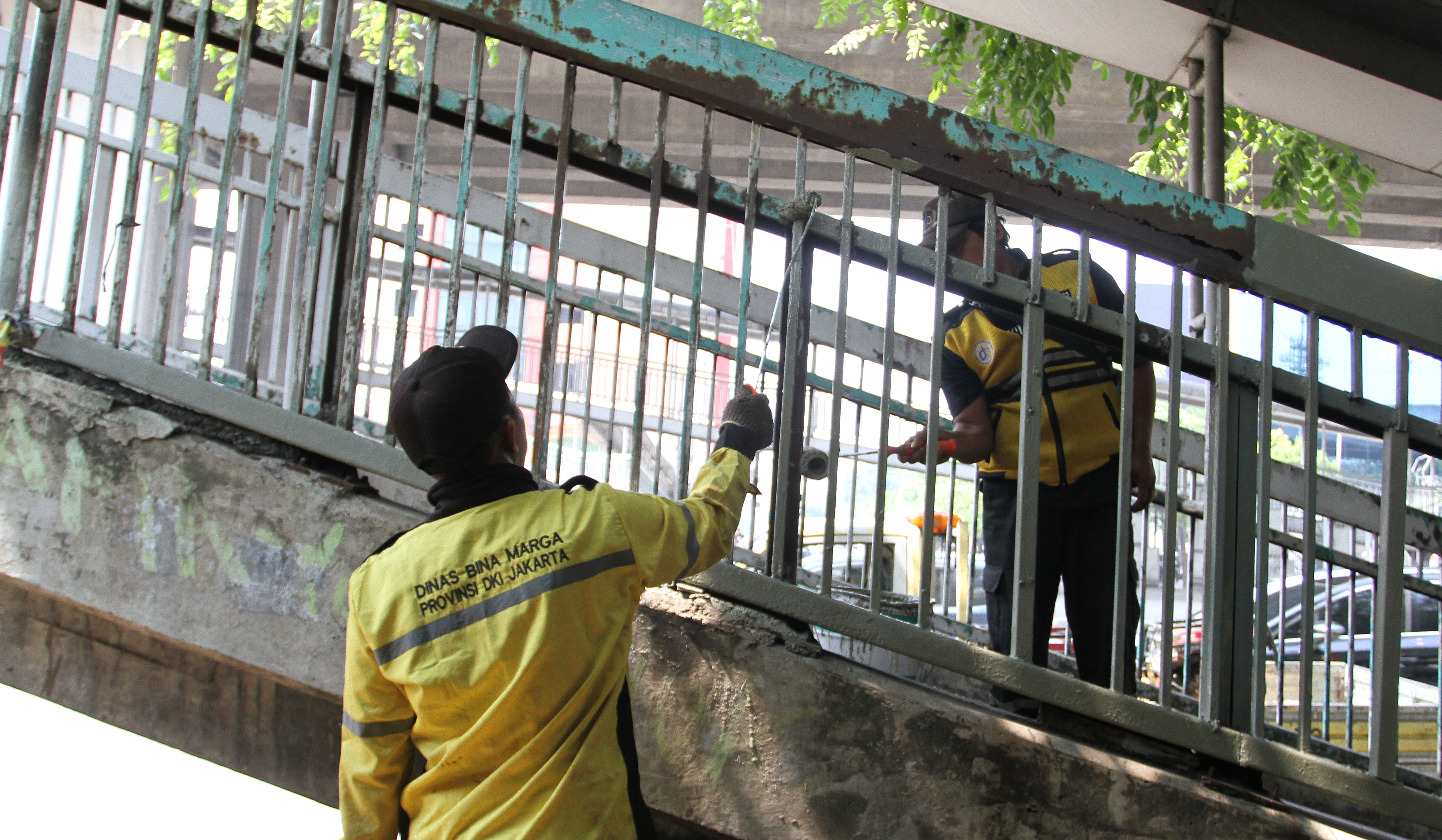 Petugas Dinas Bina Marga DKI Jakarta, memperbaiki Jembatan Penyeberangan Orang (JPO) di Jalan Yos Sudarso, Koja, Jakarta Utara. (Agus Priatna/SinPo.id)