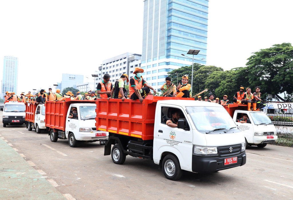 Petugas PPSU dan Dinas Bina Marga Provinsi DKI Jakarta sedang membersihkan jalan dan coretan vandalisme di tembok gedung DPR (Ashar/SinPo.id)