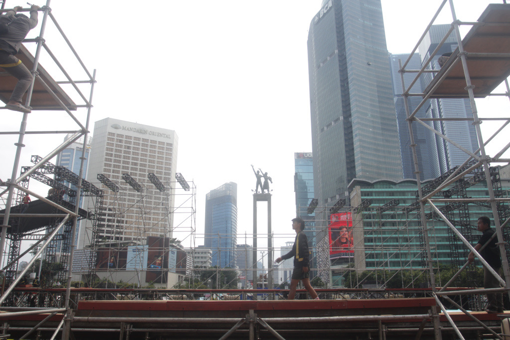 Para pekerja sedang menyelesaikan pembuatan panggung untuk penyambutan perayaan malam tahun baru (Ashar/SinPo.id)