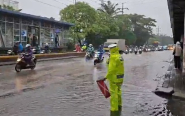 Anggota polisi saat mengatur lalin yang tergenang air (SinPo.id/TMCPoldaMetro)