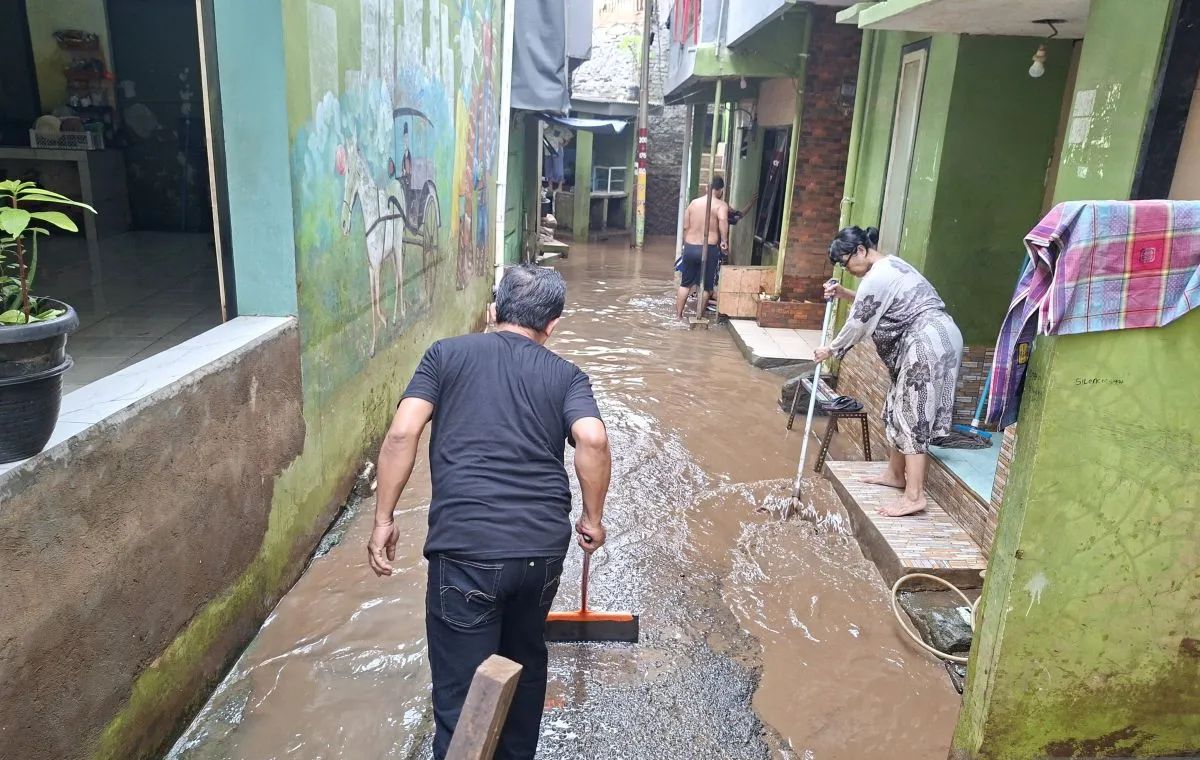 Warga Kebon Pala membersihkan lumpur dan sisa material yang terbawa air ke dalam rumah usai banjir setinggi 125 sentimeter (cm) surut di Kampung Melayu, Jakarta Timur (Jaktim). (SinPo.id/Antara)