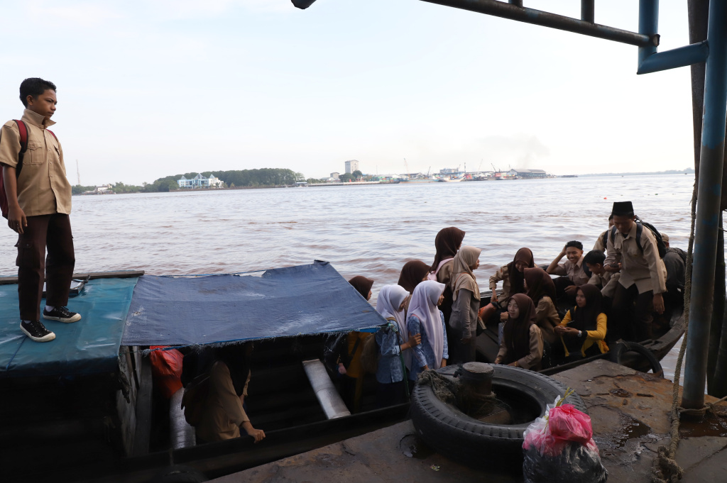 Aktivitas Anak Pulau Pucung Sebrangi Sungai Guntung Indragiri hilir Riau untuk berangkat ke Sekolah (Ashar/SinPo.id)