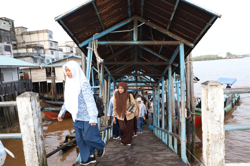 Aktivitas Anak Pulau Pucung Sebrangi Sungai Guntung Indragiri hilir Riau untuk berangkat ke Sekolah (Ashar/SinPo.id)