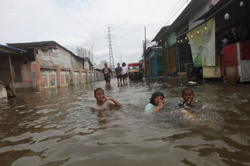 Sejumlah anak-anak sedang bermain banjir rob setinggi 30 Cm di Muara Angke (Ashar/SinPo.id)