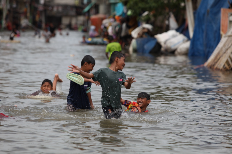 Sejumlah anak-anak sedang bermain banjir rob setinggi 30 Cm di Muara Angke (Ashar/SinPo.id)