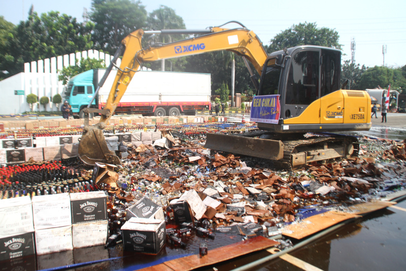 Petugas Bea Cukai sedang memusnahkan ratusan ribu botol minuman keras dan rokok ilegal yang merugikan negara sebesar Rp 165 miliar (Ashar/SinPo.id)