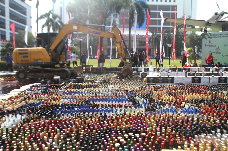 Petugas Bea Cukai sedang memusnahkan ratusan ribu botol minuman keras dan rokok ilegal yang merugikan negara sebesar Rp 165 miliar (Ashar/SinPo.id)