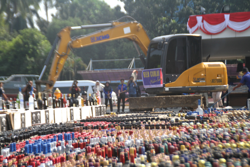 Petugas Bea Cukai sedang memusnahkan ratusan ribu botol minuman keras dan rokok ilegal yang merugikan negara sebesar Rp 165 miliar (Ashar/SinPo.id)