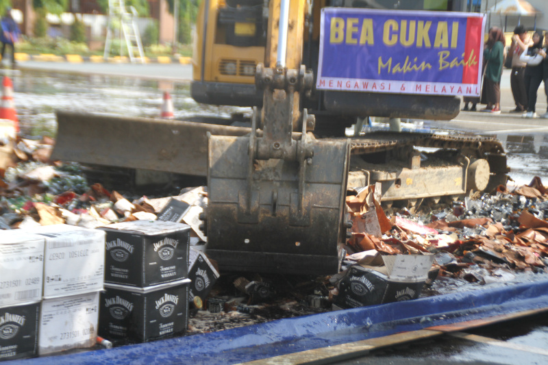 Petugas Bea Cukai sedang memusnahkan ratusan ribu botol minuman keras dan rokok ilegal yang merugikan negara sebesar Rp 165 miliar (Ashar/SinPo.id)