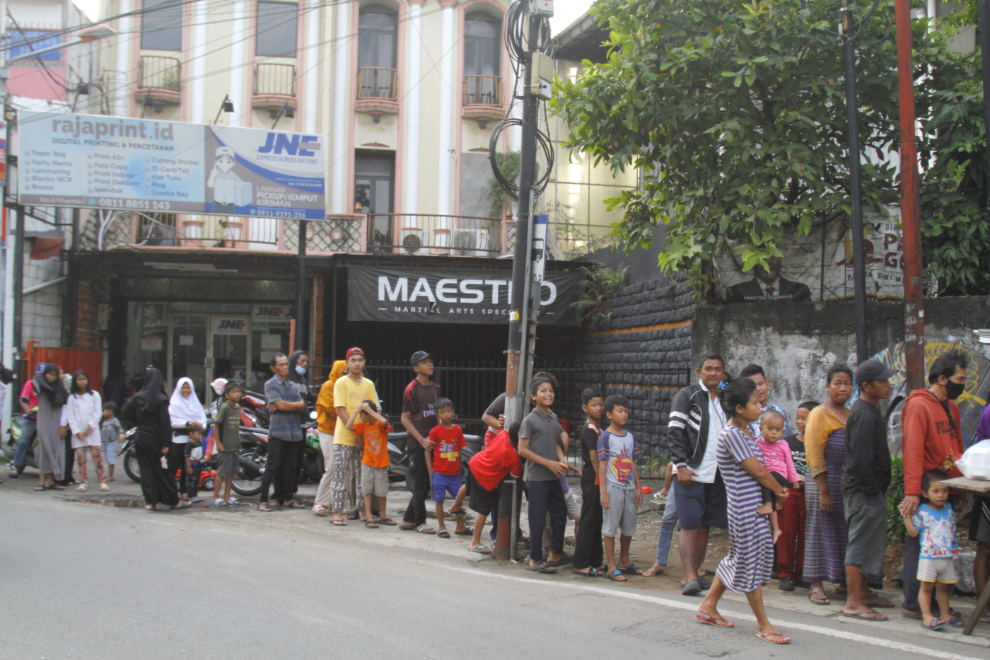 Warga antre untuk mendapatkan bubur ayam gratis yang dibagikan selama Bulan Suci Ramadan di Jalan Kebayoran Lama (Ashar/SinPo.id)