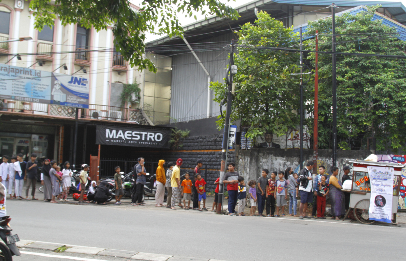 Warga antre untuk mendapatkan bubur ayam gratis yang dibagikan selama Bulan Suci Ramadan di Jalan Kebayoran Lama (Ashar/SinPo.id)