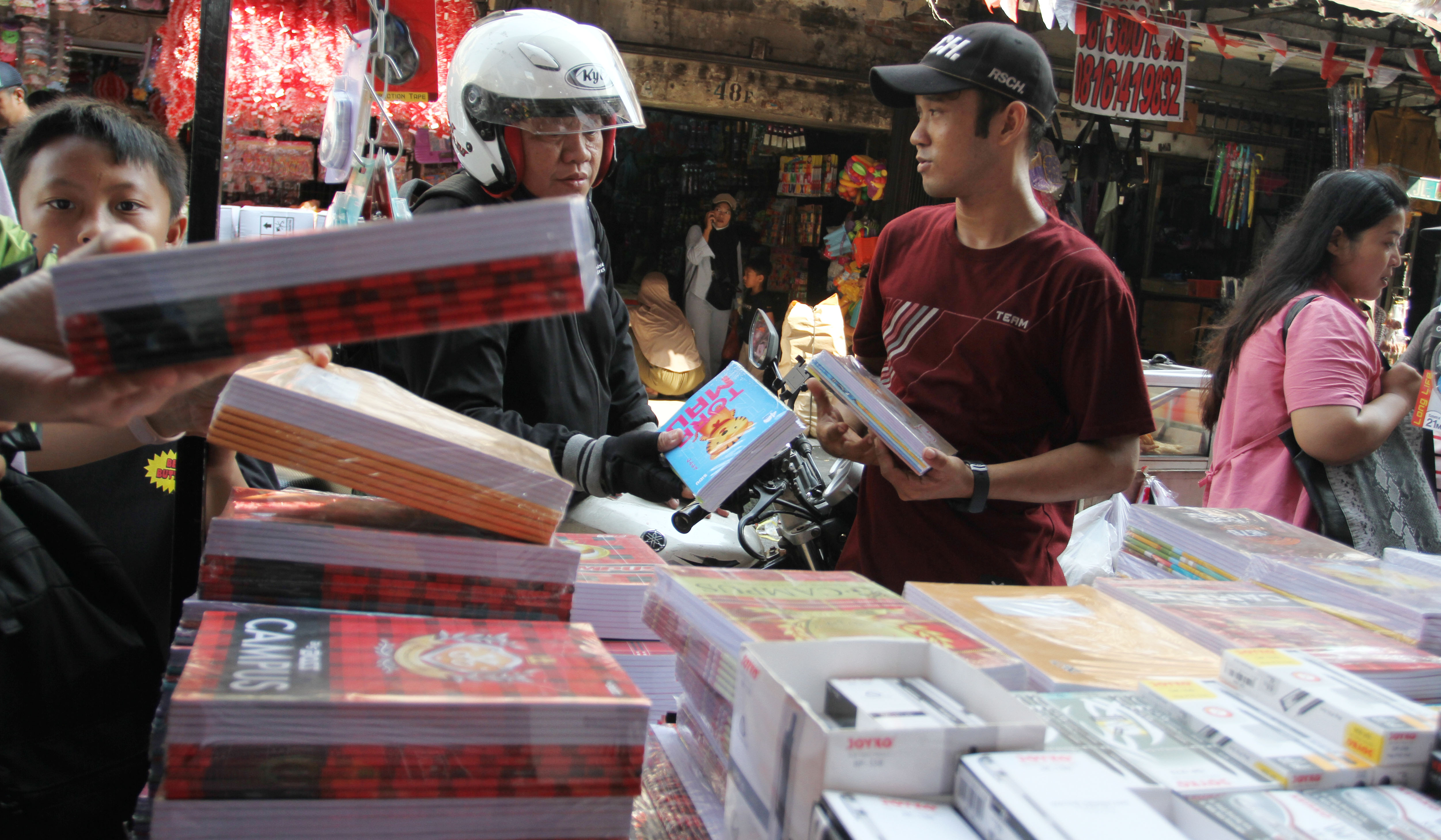 Pengunjung melihat buku tulis yang dijual di pasar pagi Asemka, Jakarta. (Agus Priatna/SinPo.id)