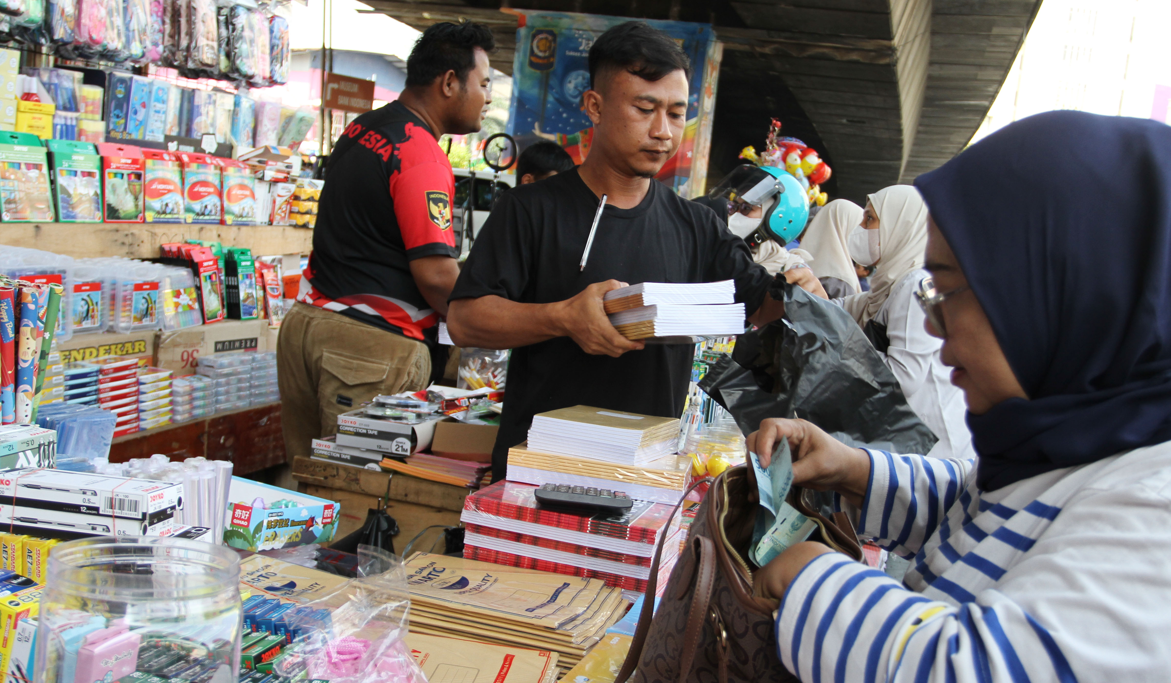 Pengunjung melihat buku tulis yang dijual di pasar pagi Asemka, Jakarta. (Agus Priatna/SinPo.id)