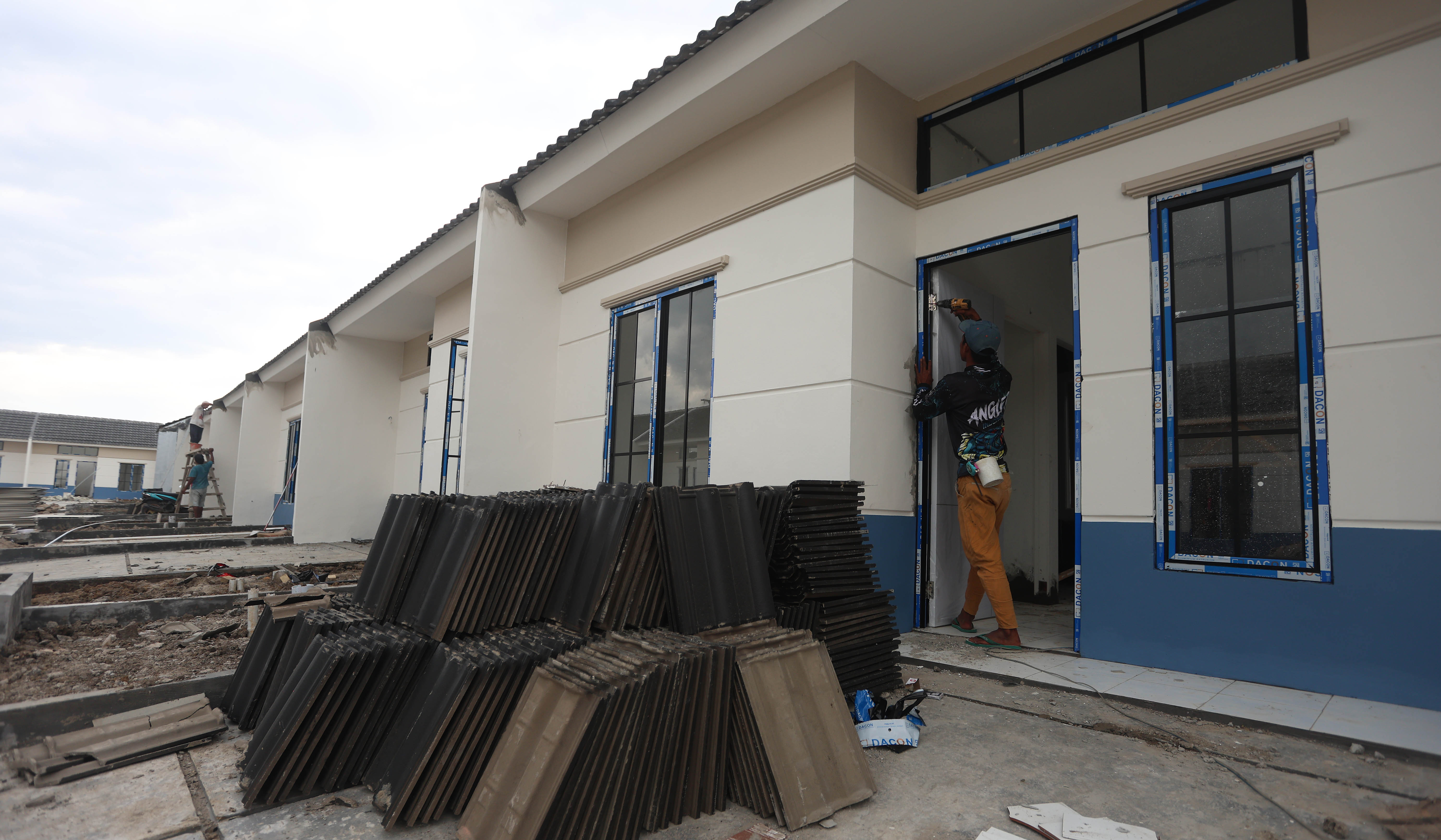 Pekerja menyelesaikan pembangunan rumah subsidi. (Agus Priatna/SinPo.id)