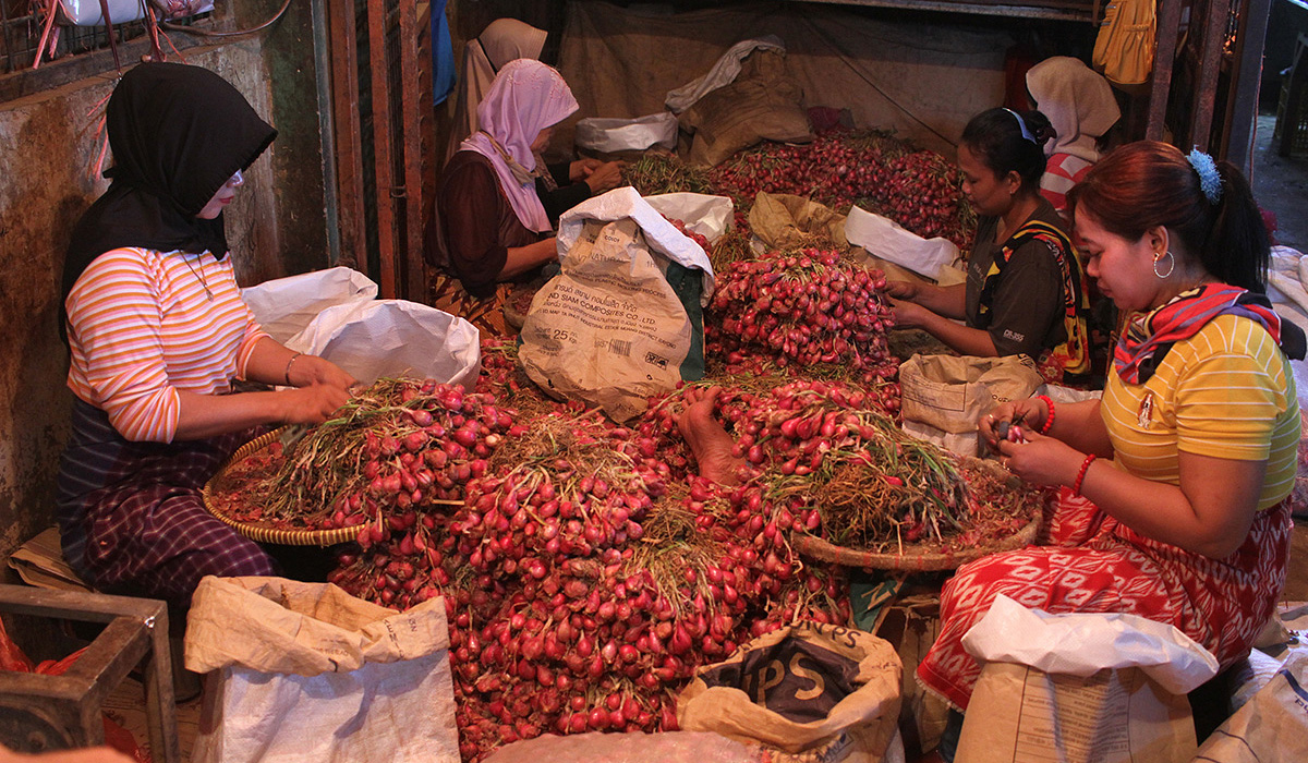 Pekerja mengupas bawang merah di Pasar Induk Kramat Jati. (Agus Priatna/SinPo.id)