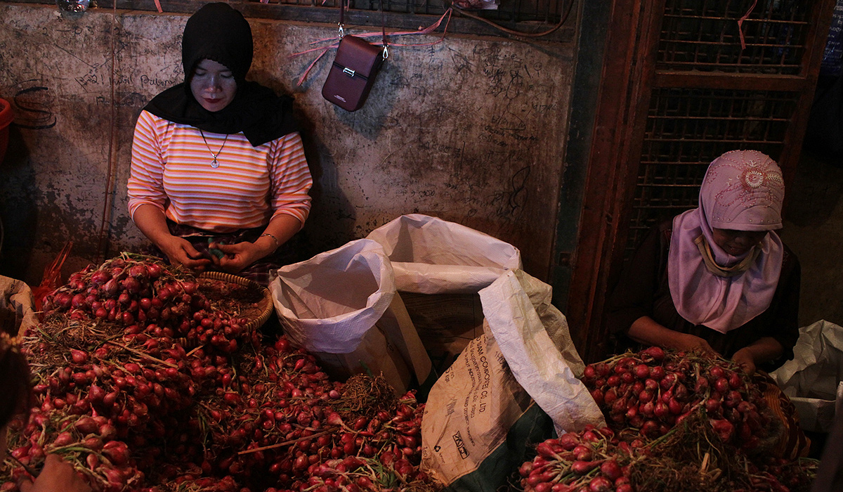 Pekerja mengupas bawang merah di Pasar Induk Kramat Jati. (Agus Priatna/SinPo.id)