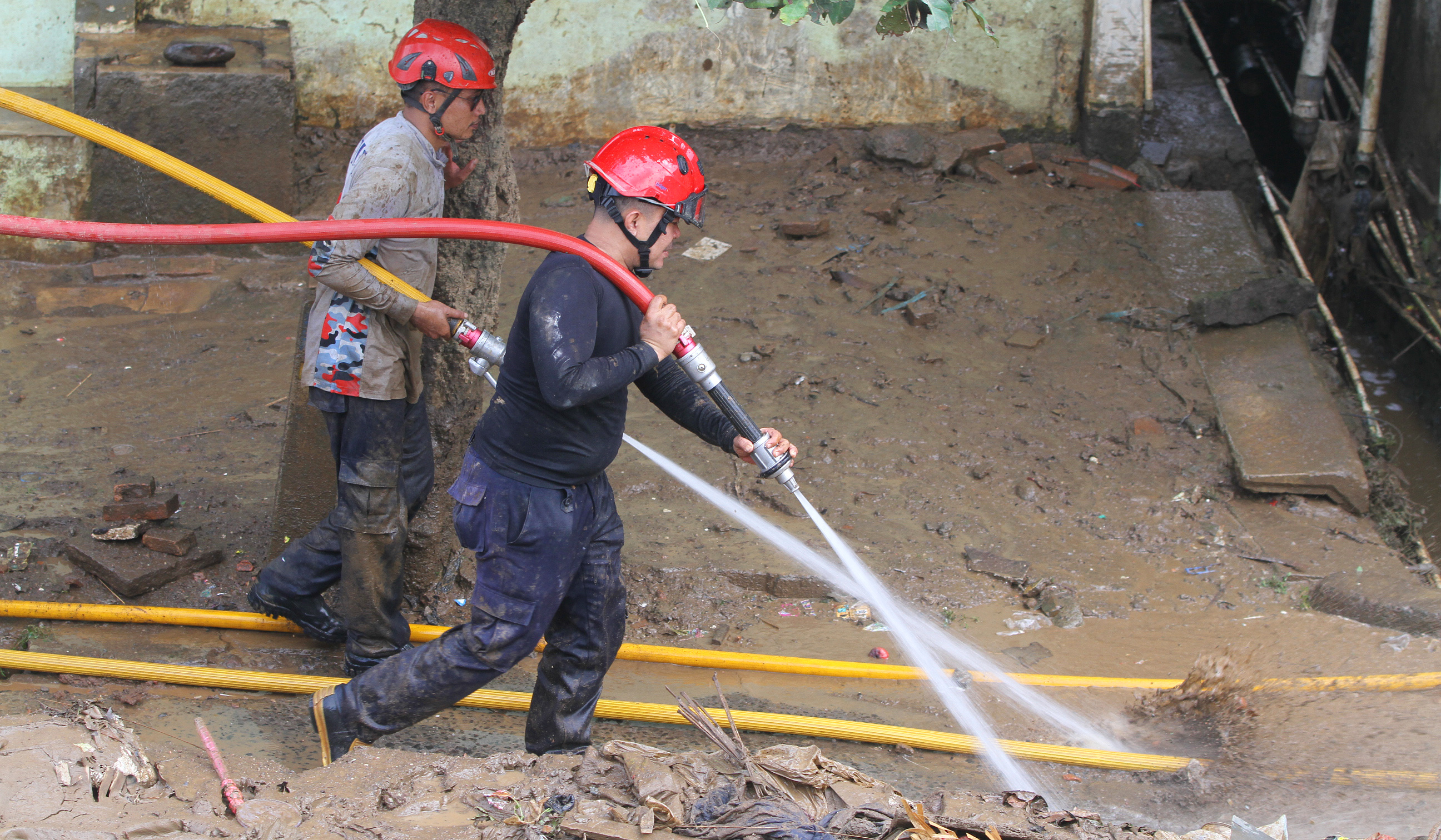 Petugas pemadam kebakaran (Damkar) membantu membersihkan lumpur sisa banjir di Rawajati, Jakarta, Senin (7 Juli 2025).