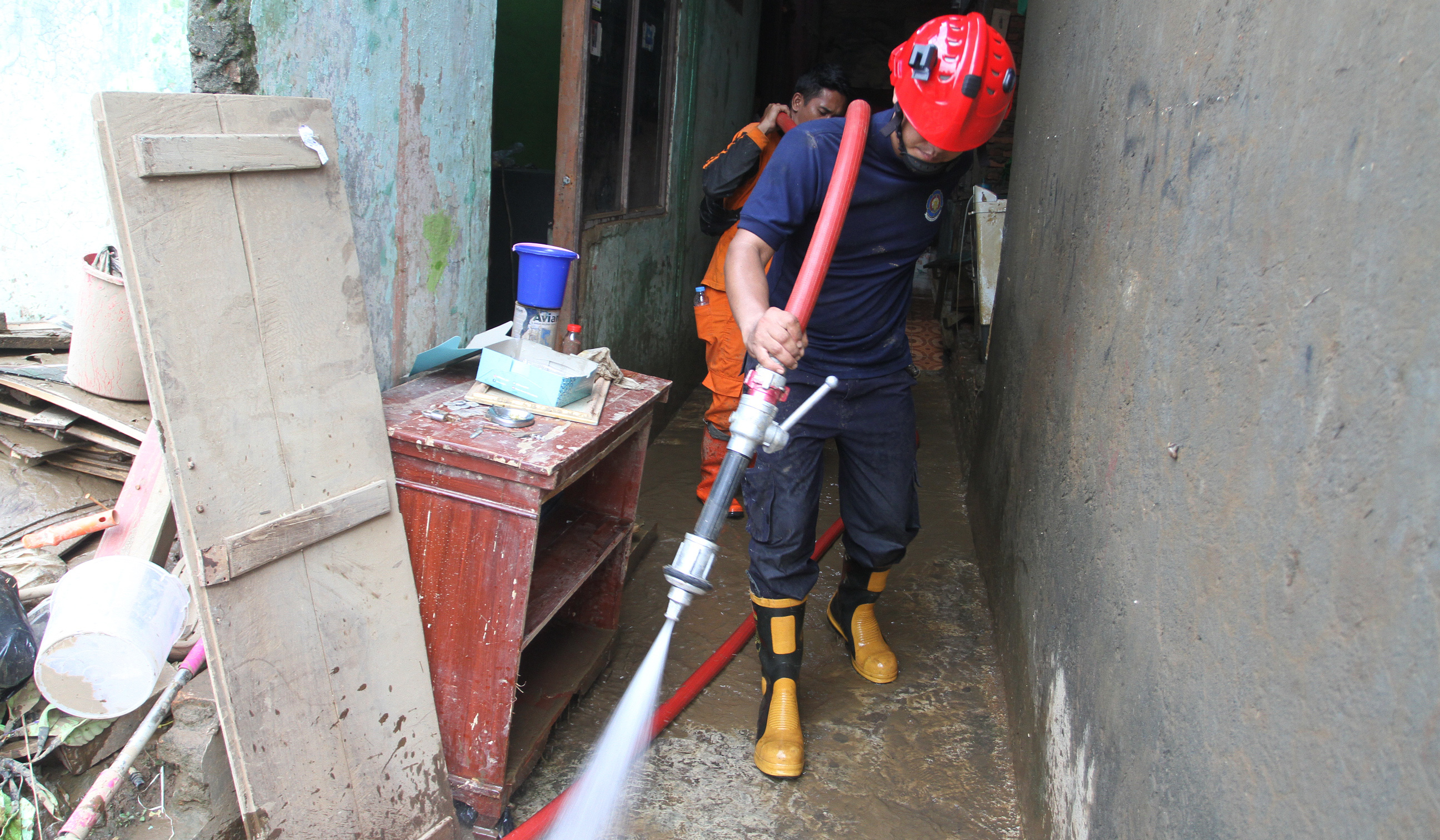 Petugas pemadam kebakaran (Damkar) membantu membersihkan lumpur sisa banjir di Rawajati, Jakarta, Senin (7 Juli 2025).