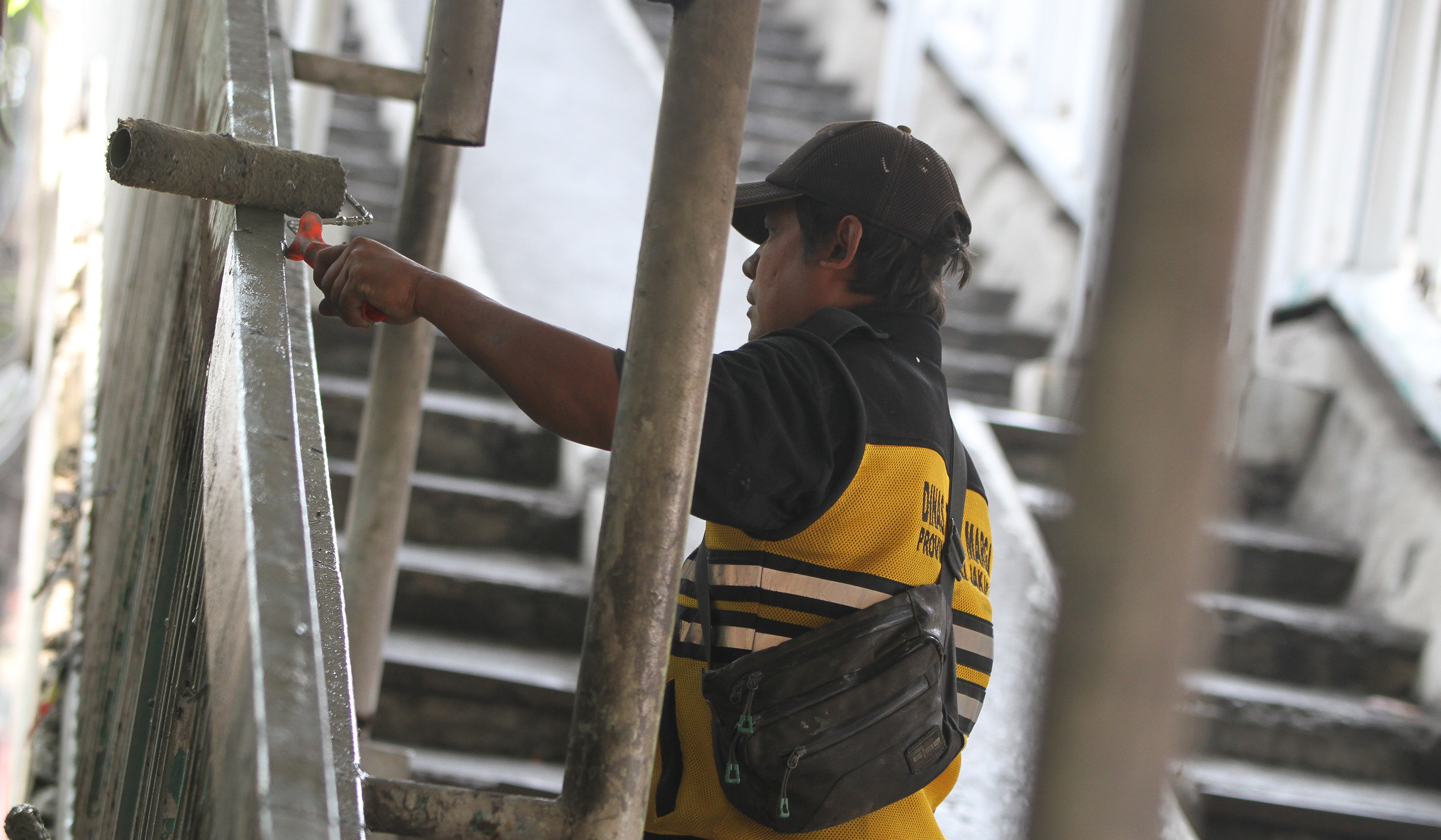Petugas Dinas Bina Marga DKI Jakarta, memperbaiki Jembatan Penyeberangan Orang (JPO) di Jalan Yos Sudarso, Koja, Jakarta Utara. (Agus Priatna/SinPo.id)