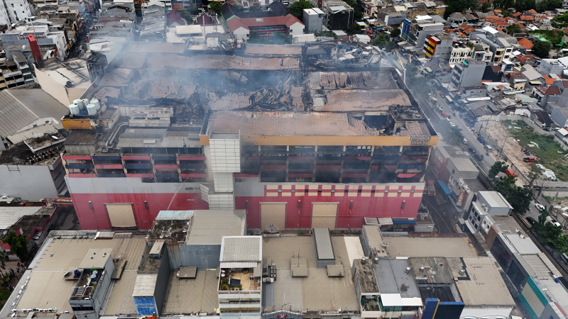 Petugas Damkar sedang melakukan penyemprotan dan pendinginan agar tidak terjadi api muncul kembali di Glodok Plaza (Ashar/SinPo.id)