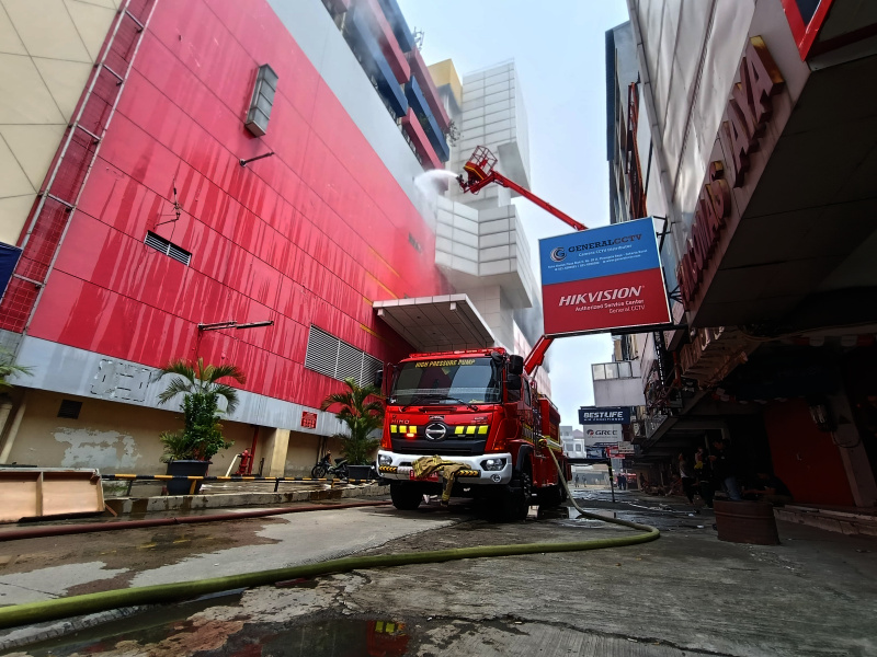 Petugas Damkar sedang melakukan penyemprotan dan pendinginan agar tidak terjadi api muncul kembali di Glodok Plaza (Ashar/SinPo.id)