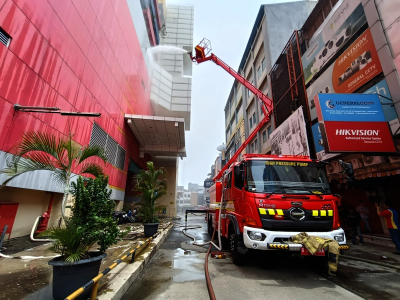 Petugas Damkar sedang melakukan penyemprotan dan pendinginan agar tidak terjadi api muncul kembali di Glodok Plaza (Ashar/SinPo.id)