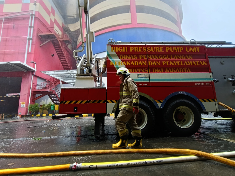 Petugas Damkar sedang melakukan penyemprotan dan pendinginan agar tidak terjadi api muncul kembali di Glodok Plaza (Ashar/SinPo.id)