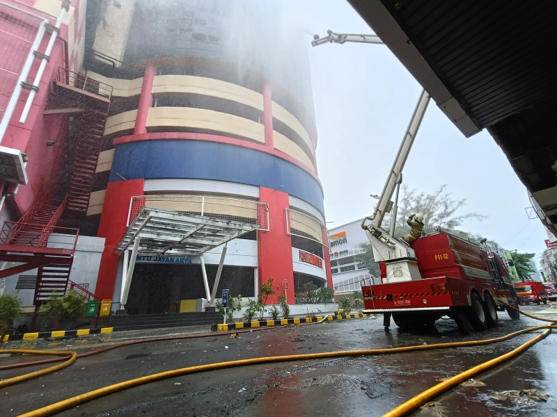 Petugas Damkar sedang melakukan penyemprotan dan pendinginan agar tidak terjadi api muncul kembali di Glodok Plaza (Ashar/SinPo.id)