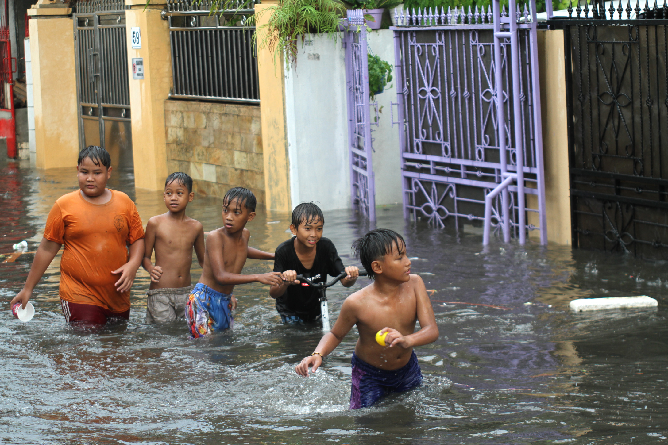 Anak-anak sedang bermain air banjir Rawa Belong (Ashar/SinPo.id)