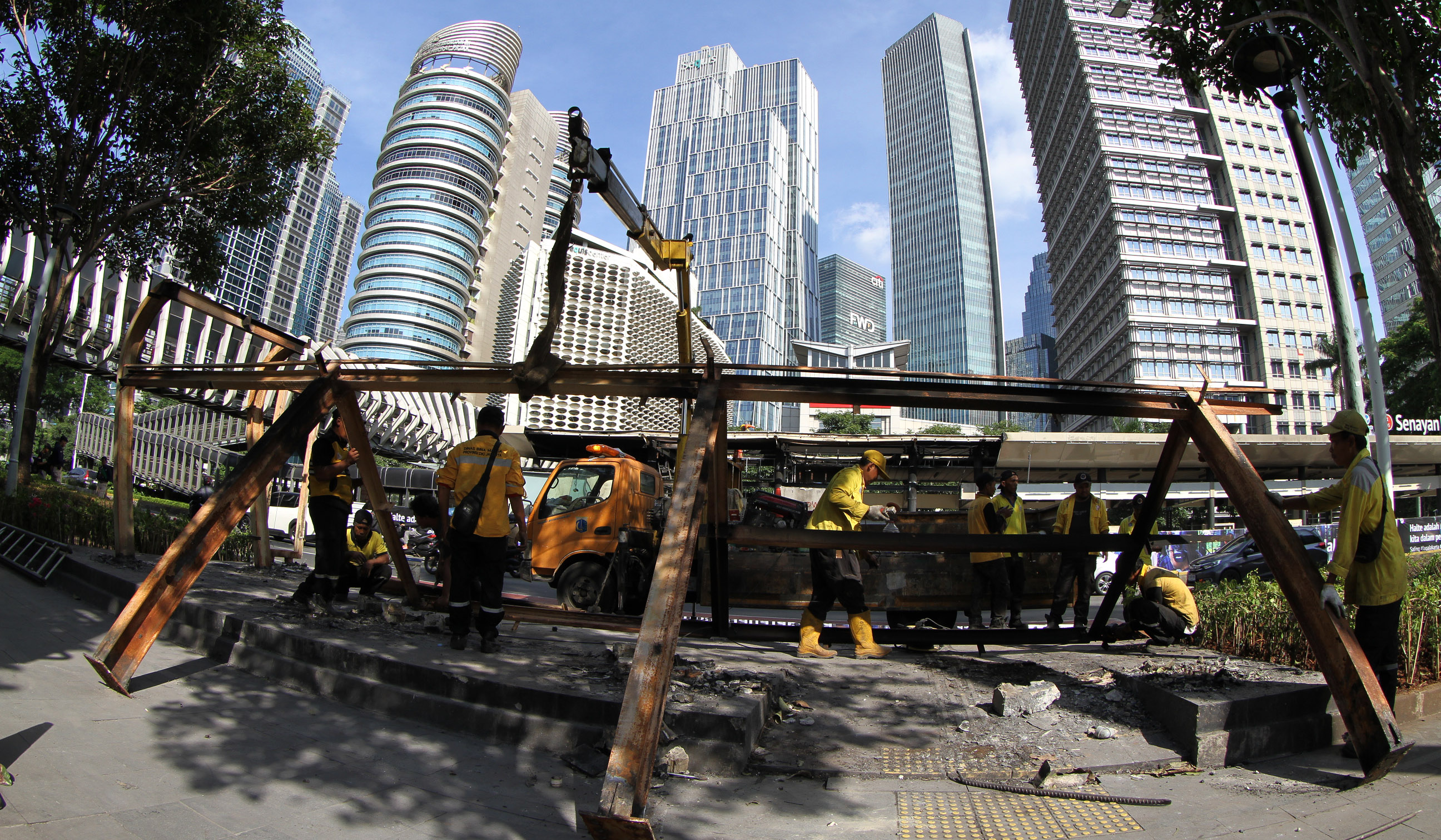 Petugas membersihkan halte yang terbakar di jalan Jenderal Sudirman, Jakarta. (Agus Priatna/SinPo.id)