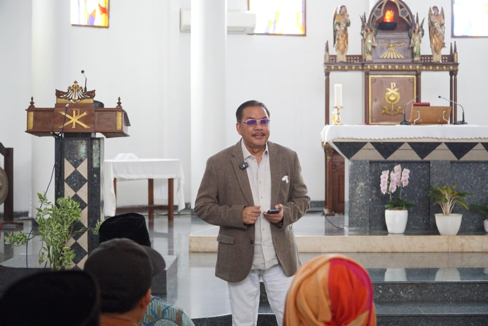 Ketua Esoterika Forum Spiritualitas, Denny JA menyerahkan lukisan kepada Pastor Kepala Paroki Gereja Katolik Santo Servatius Romo Yohanes Wartaya SJ di Kampung Sawah Bekasi (Ashar/SinPo.id)