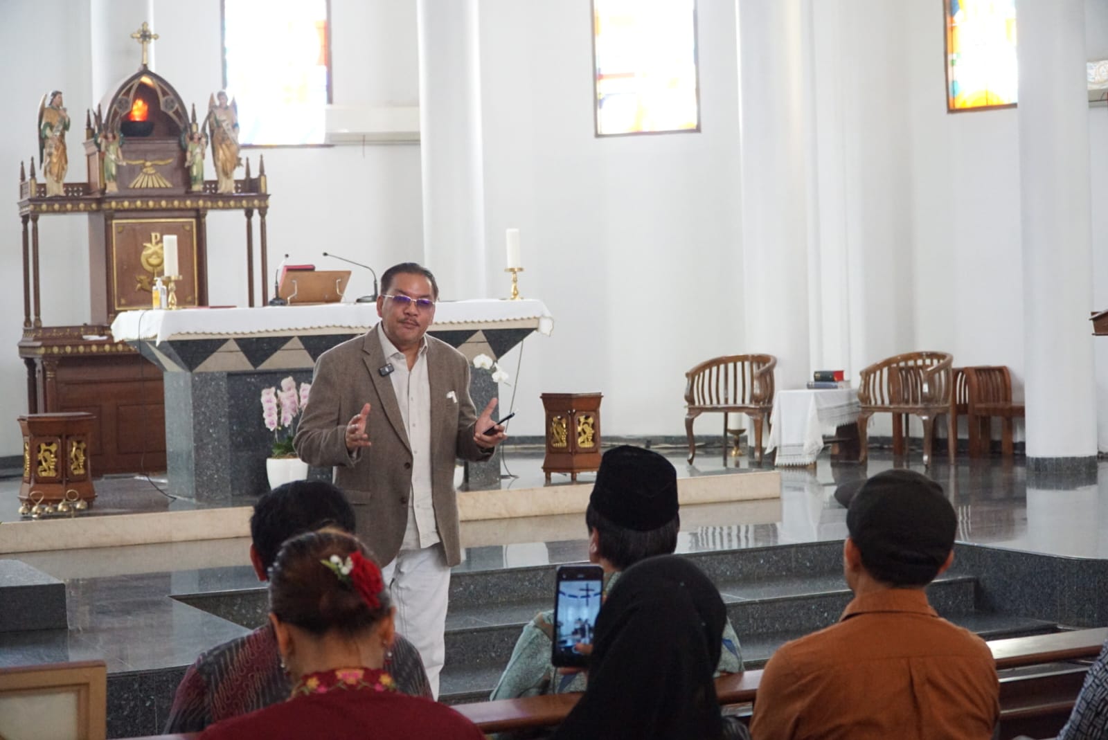 Ketua Esoterika Forum Spiritualitas, Denny JA menyerahkan lukisan kepada Pastor Kepala Paroki Gereja Katolik Santo Servatius Romo Yohanes Wartaya SJ di Kampung Sawah Bekasi (Ashar/SinPo.id)