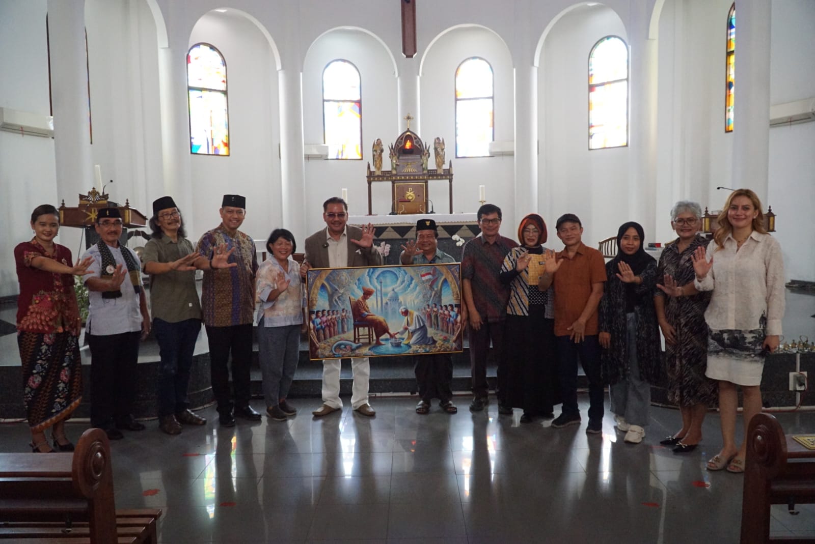 Ketua Esoterika Forum Spiritualitas, Denny JA menyerahkan lukisan kepada Pastor Kepala Paroki Gereja Katolik Santo Servatius Romo Yohanes Wartaya SJ di Kampung Sawah Bekasi (Ashar/SinPo.id)