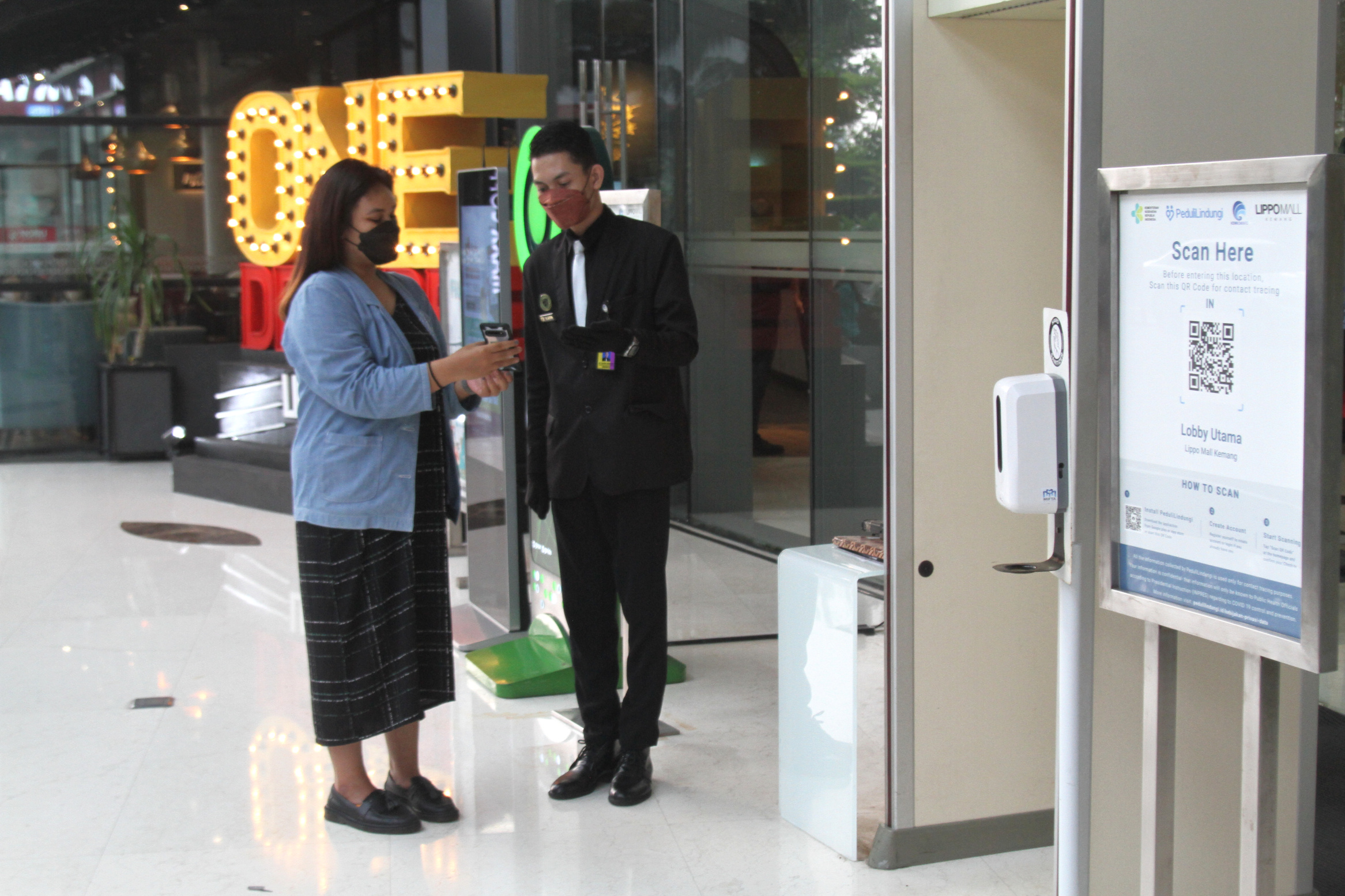 Pengunjung mall me-scan aplikasi pedulilindungi.id syarat masuk mall(Ashar/SinPo.id)
