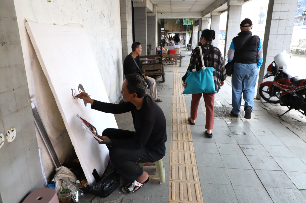 Pak Mardi Pelukis jalanan Kota Tua sedang menyelesaikan karya lukisannya (Ashar/SinPo.id)
